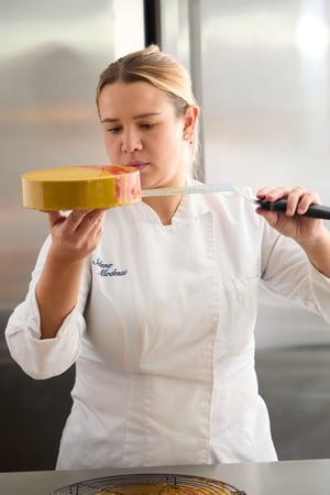 Selene Modesti rifinisce a mano una torta moderna glassata nel laboratorio di Selene Pastry Details, curando con precisione ogni dettaglio della decorazione.