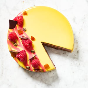 Torta moderna artigianale di Selene Pastry Details con glassa specchiata, lamponi freschi e decorazioni di cioccolato, realizzata per occasioni speciali